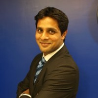 Person smiling in a suit against a blue background.