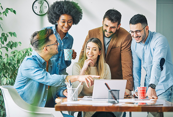 Group of people smiling and working around a laptop.