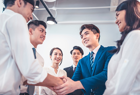 Group of people in business attire shaking hands in an office.