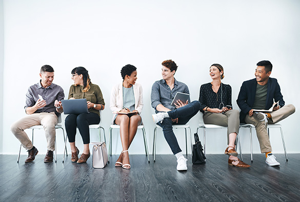 A diverse group of people sitting in chairs, chatting and laughing.