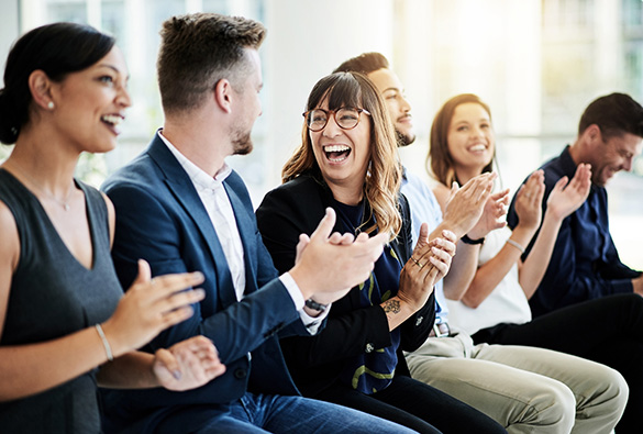 Group of people sitting in a row, smiling and clapping.