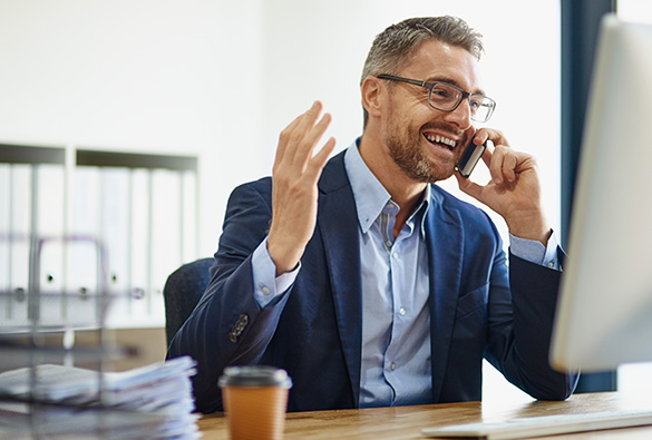 Person in a business suit talking on the phone at a desk.