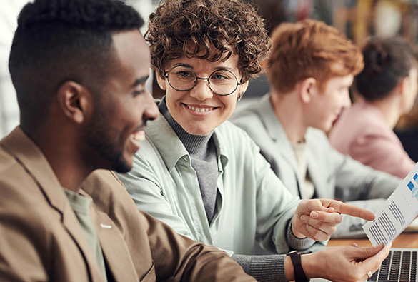 People in a meeting, sharing documents and smiling.