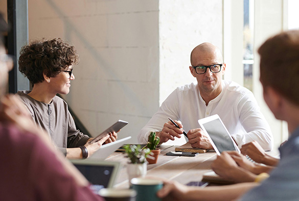 People having a meeting around a table with laptops and tablets.