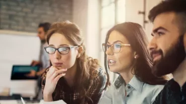 Group of people working together at a computer screen.