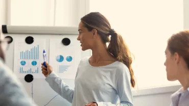 Person giving a presentation with graphs on a flipchart.