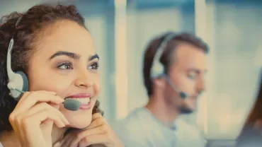Customer service representatives wearing headsets and working at their desks.