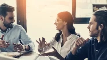 Group of people having a lively discussion in an office setting.