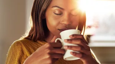 Person enjoying a cup of coffee in warm sunlight.