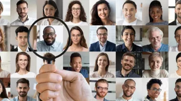 Collage of diverse smiling individuals with a magnifying glass focusing on one person.