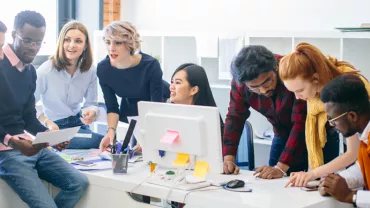 Group of colleagues collaborating around a desk in an office.