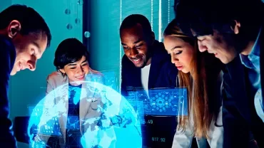 Group of people collaborating around a digital globe projection.