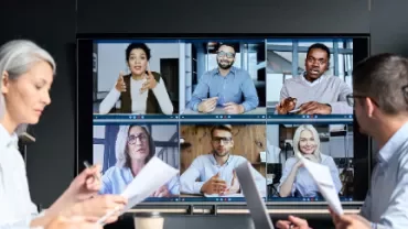 People in a meeting room watching a video conference on a large screen.