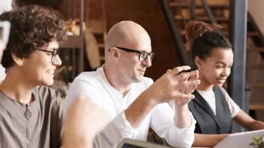 Group of people collaborating at a table with laptops.