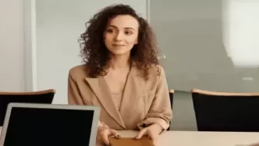 a girl smiling sitting in an office with two other people