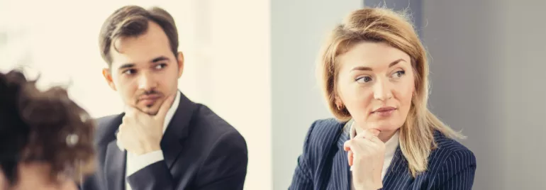 People in business attire sitting and listening in a meeting.