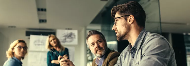 People in a meeting room discussing with papers on wall.