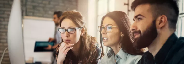 Group of people working together at a computer screen.