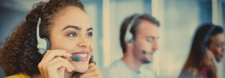 Customer service representatives wearing headsets and working at their desks.
