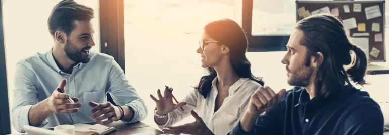 Three people having a lively discussion around a table.