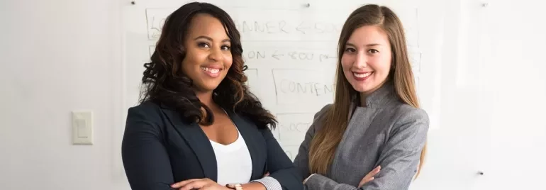 Two professionals smiling, standing in front of a whiteboard.