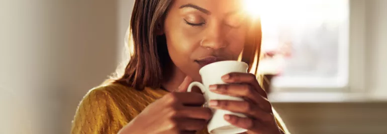 Person enjoying a cup of coffee in warm sunlight.