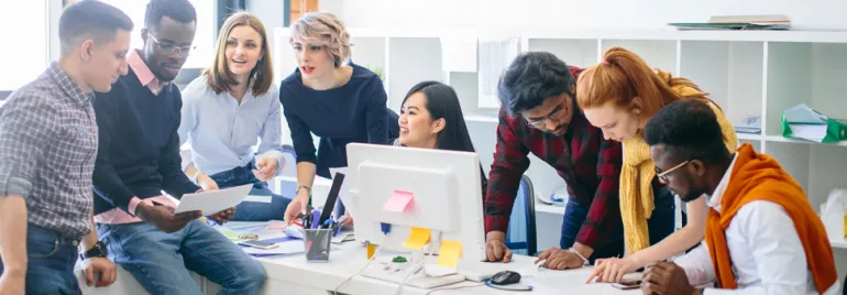Group of colleagues collaborating around a desk in an office.
