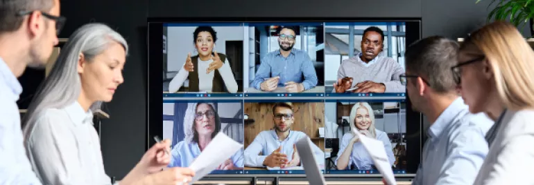 People in a meeting room watching a video conference on a large screen.
