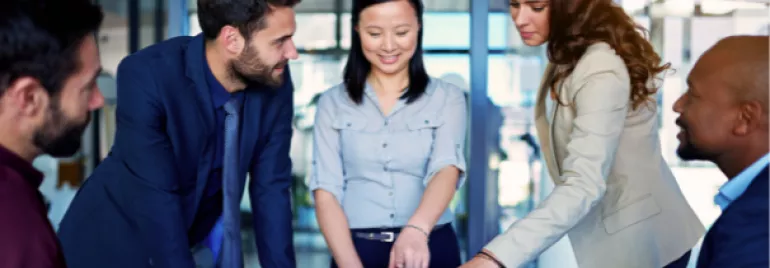 Group discussion around a laptop in a modern office.