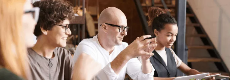 Group of people collaborating at a table with laptops.