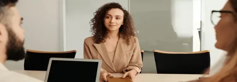 a girl smiling sitting in an office with two other people