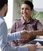 Two people shaking hands, one smiling, in a professional setting.