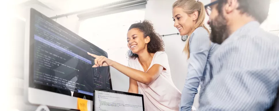 Smiling team collaborating on a coding project in an office.
