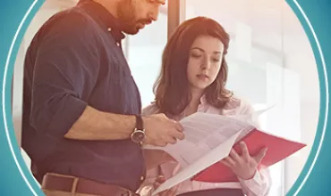 Two people reviewing documents in an office setting.