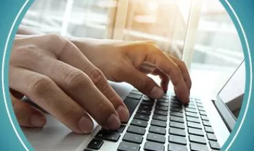 Close-up of hands typing on a laptop keyboard.