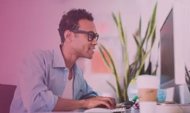 Person working at a desk with a computer and a coffee cup.
