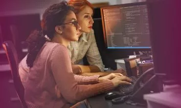 Two people working on computers with code on screens.