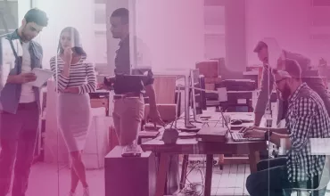 Group of people collaborating in a modern office with computers and papers.