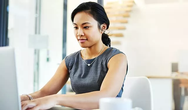 Person typing on a laptop in a modern office setting.