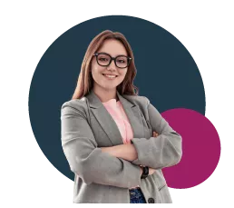 Person with long hair and glasses, wearing a gray blazer with a pink top, smiling confidently.